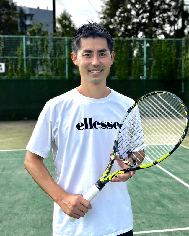 テニスコートでラケットを持つ赤羽 毅朗さん